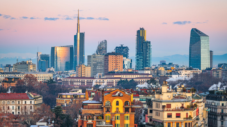 City skyline of Milan, Italy during sunset hours with old and modern buildings shown throughout the city.