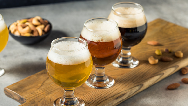 A flight of three different craft beers on a wooden board
