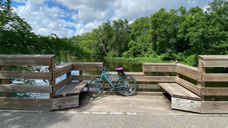a bike leaning against a wooden bench overlooking a lake