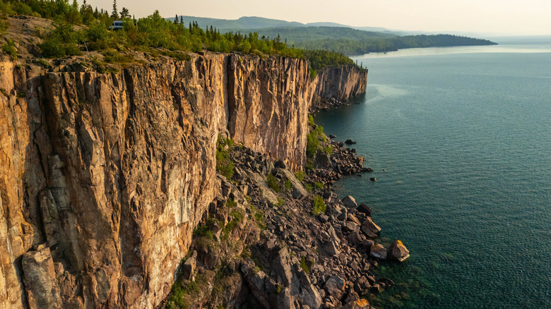 The sheer face of Palisade Head with a rocky bottom over Lake Superior on a sunny day.