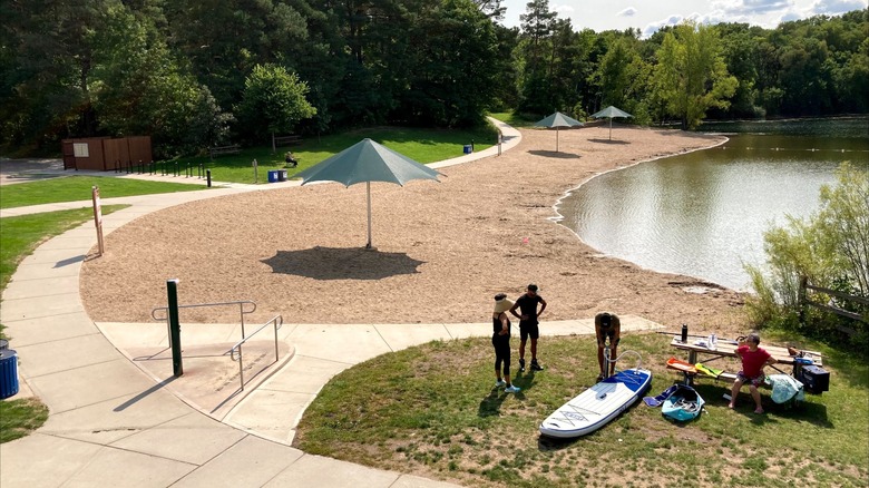 Sandy beach at Schulze Lake with people getting ready to kayak at Lebanon Hills Regional Park, Minnesota