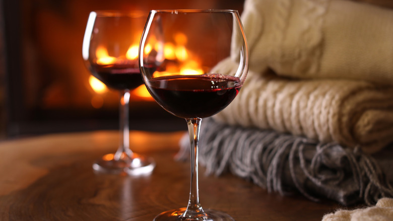 Two wine glasses and blankets in front of fire