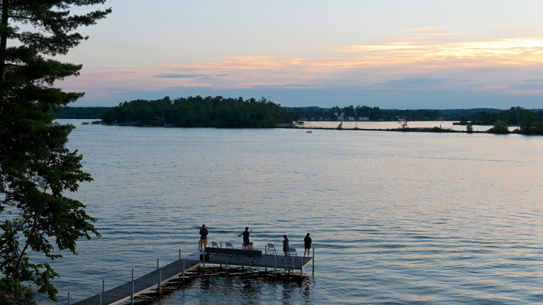People fishing off the dock on lake at sunset