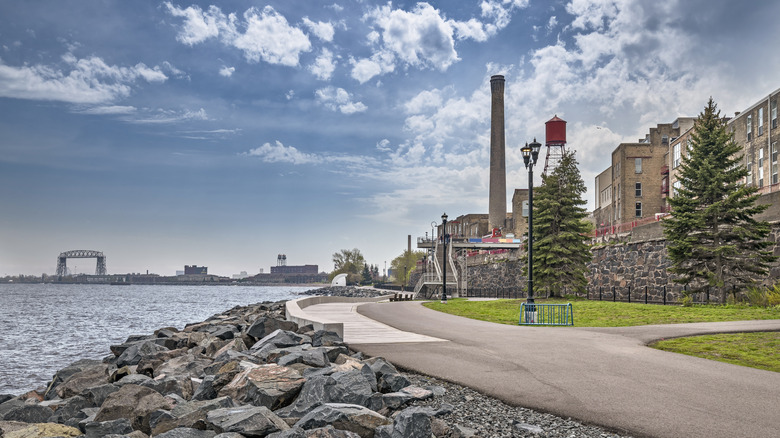 Paved walkway along shoreline with lift bridge in distance