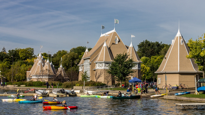 Boats heading out on the water next to the pointed buildings of Lake Harriet