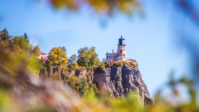 Lighthouse on cliff framed by leaves