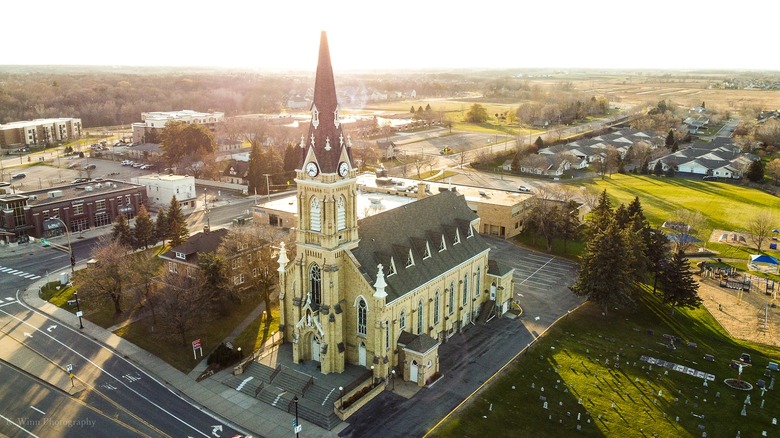 An aerial view of the neo-gothic St. Michael Catholic Church on the corner of two roads with buildings and houses behind it