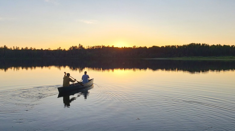 Canoeists paddle across Indian Lake at sunset in Cloquet Valley State Forest, Minnesota