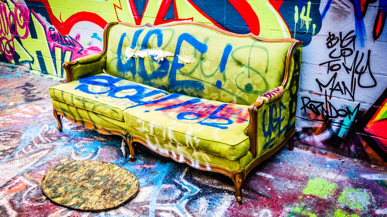 A sofa, wall, and footpath covered in vibrant graffiti and street art in Graffiti Alley in Station North.