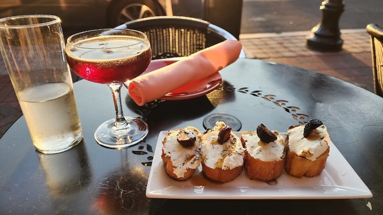 A plate of cream cheese and olive bread tapas with a glass of sangria sitting on an outdoor table at Tapas Teatro.