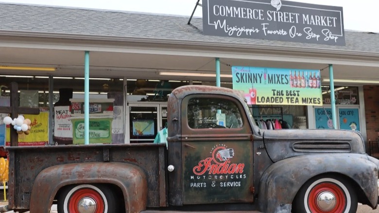 An old-fashioned pickup truck in front of a store