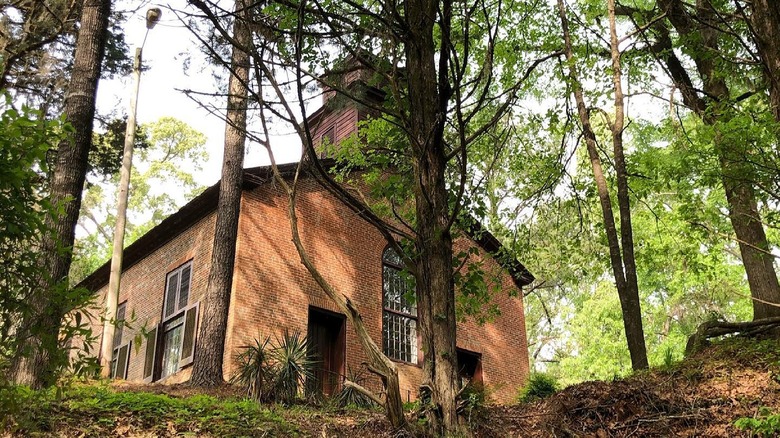 View of the 1837 methodist church at Rocky Springs through leafy trees.