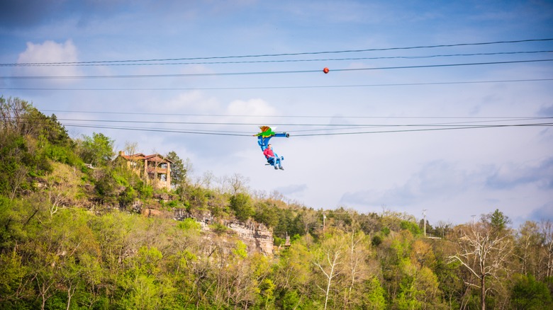 A man riding a sit-down zipline over trees at Lake Taneycomo, Missouri