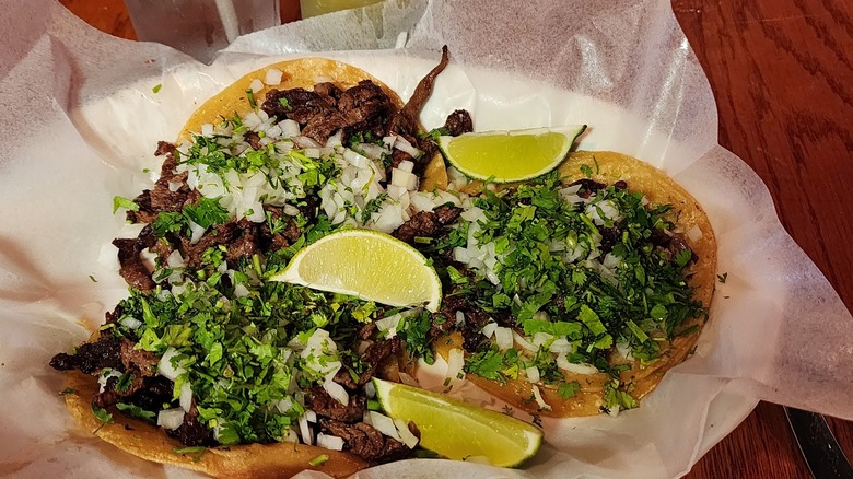 Carne asada tacos topped with chopped onion and cilantro, served with lime wedges at Dos Arcos in Mexico, Missouri