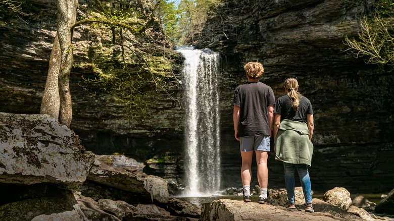 Couple hiking near a waterfall on a trail in the Ozarks