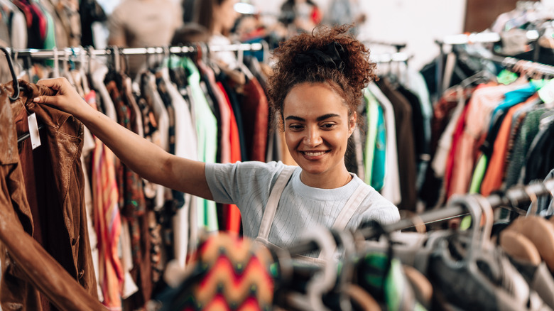 Woman happily perusing clothes in shop