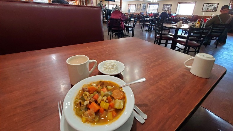 A plate of food and coffee on the table at Dino's Diner with view of the restaurant