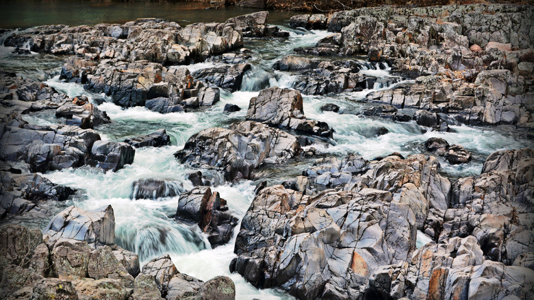 Blue water cascades over geometric gray rocks