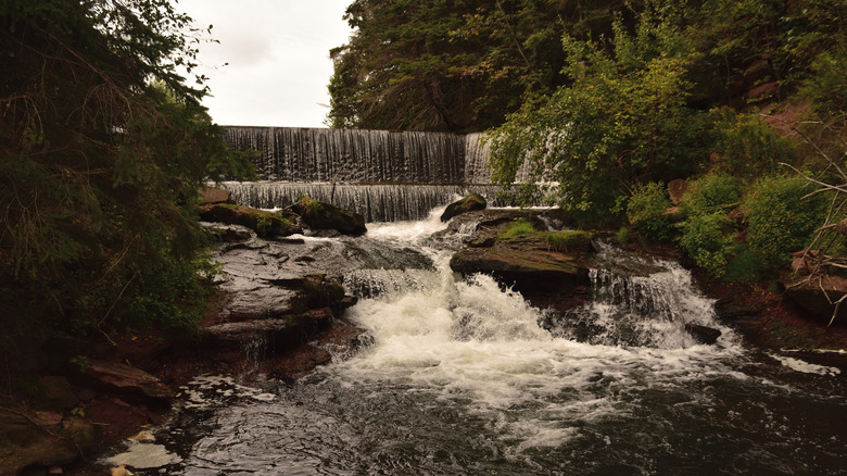 An artificial waterfall pours over rocks on a cloudy summer day on Prince Edward Island, Canada