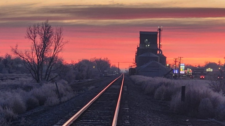 View down railroad tracks toward small town with deep pink sunset