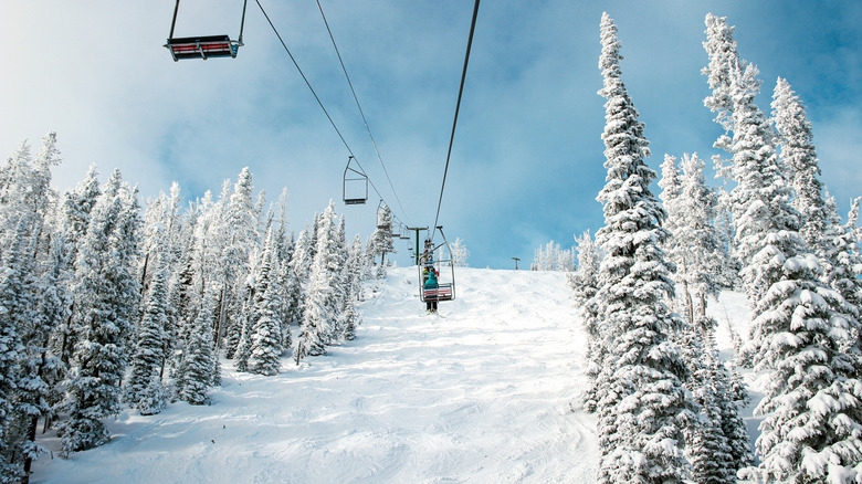 Skier on a chair lift ascending the mountain at Showdown, Montana