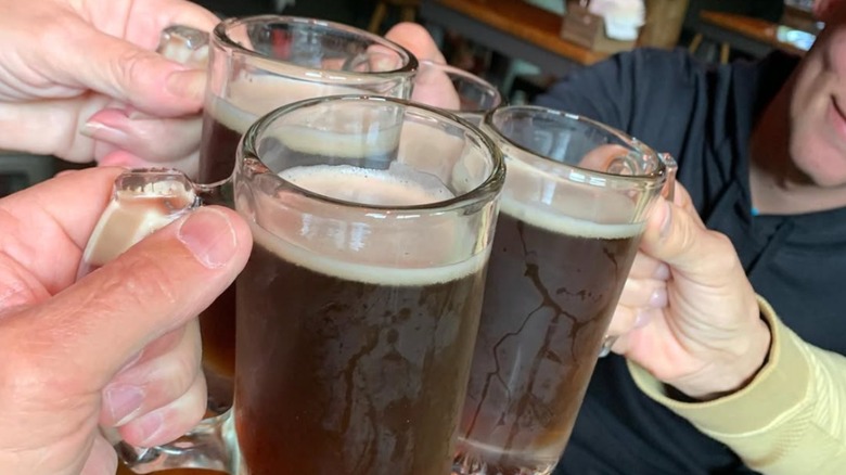 People toasting with big glasses of Moose Drool brown ale in a bar.