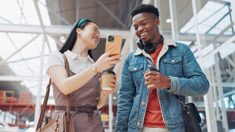 A young woman shows something on her smartphone to her friend
