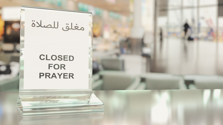 A café with a sign on the counter telling customers that it is "Closed for prayer" in English and Arabic text