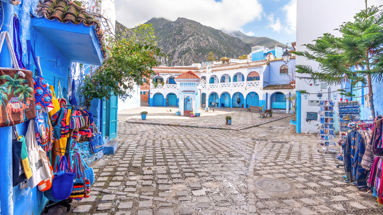 A street lined with crafts and clothes leading to a square in Chefchaouen, Morocco