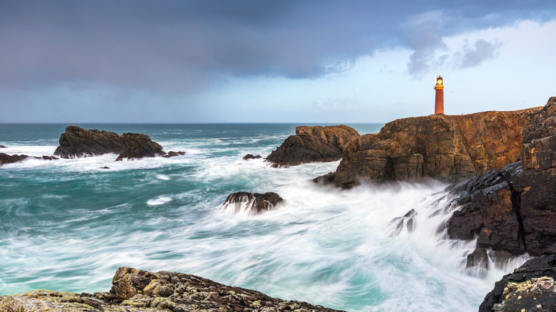 Waves crash at the surface of the cliff on which the Butt of Lewis Lighthouse stands