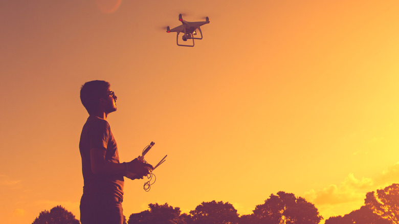 A man flying a drone at sunset