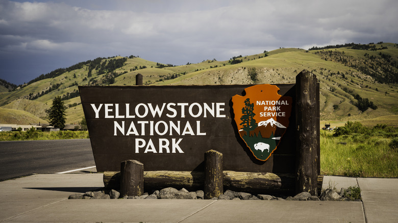 The sign at an entrance to Yellowstone National Park, surrounded by trees and hills