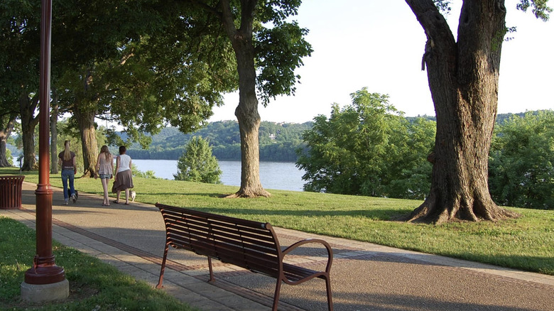 A trail along the Ohio River with a bench and people walking at Fernbank Park.