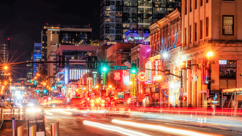 street with neon signs, tall buildings, light streaks from passing cars