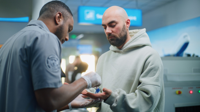 TSA Officer swabs man's hands at security checkpoint