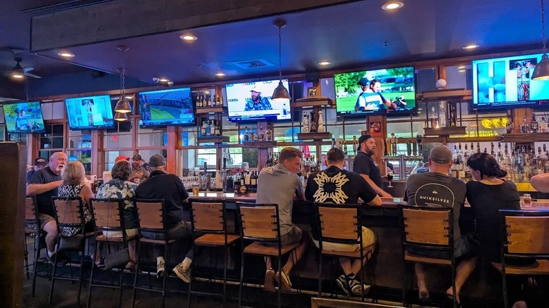 Several patrons sitting at bar under TVs showing sports at Tavern in the Forest in Myrtle Beach