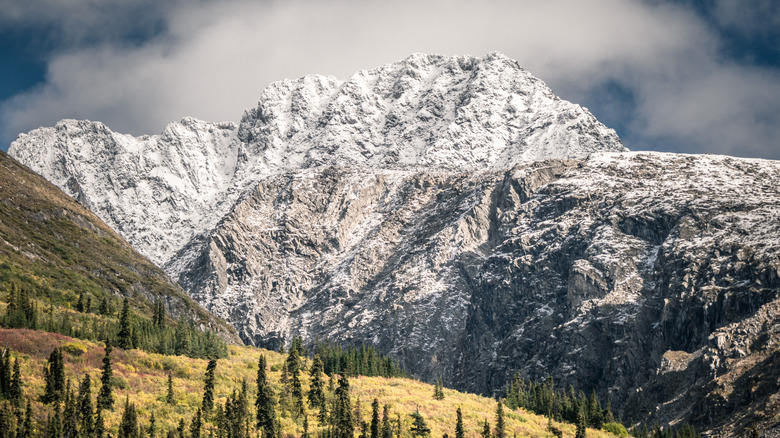 A massive snow covered mountain and rolling hills within the Nahanni National Park reserve in the Northwest Territories, Canada