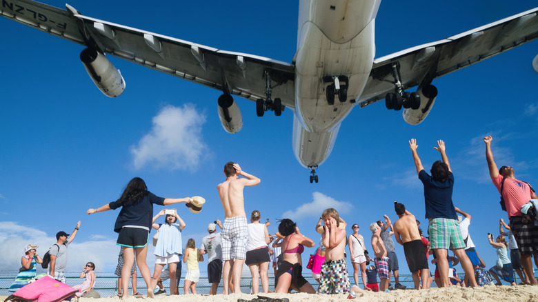 Tourists watch from the beach as a jumbo jet takes off