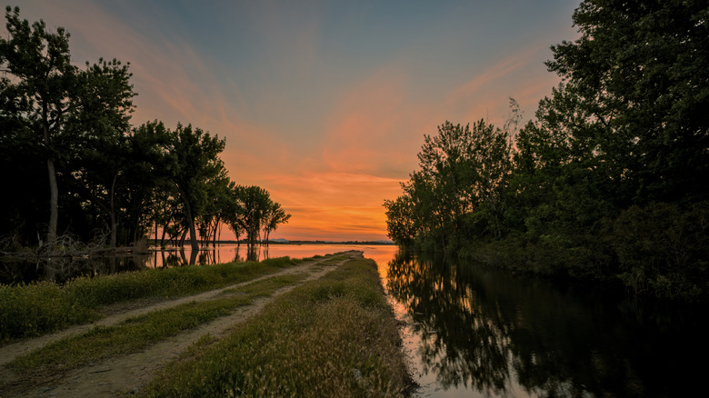 A dirt path leading to Lake Lowell near Nampa under the orange hues of sunset.