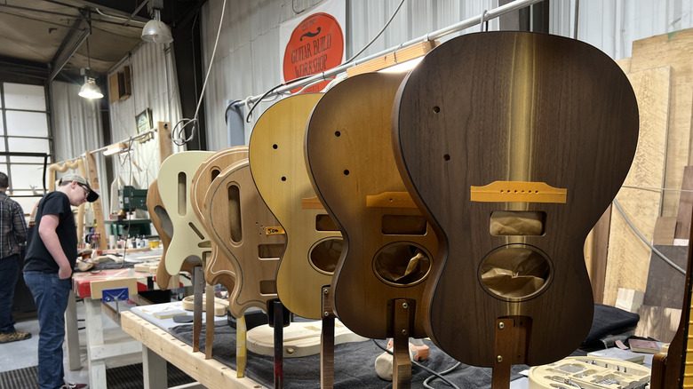 Guitars lined up at Guitar Build Workshop, with people in the background