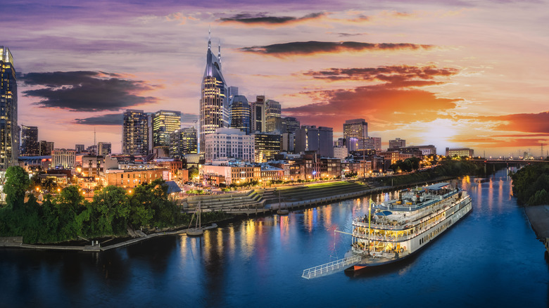 Nashville skyline at dusk with riverboat cruising by