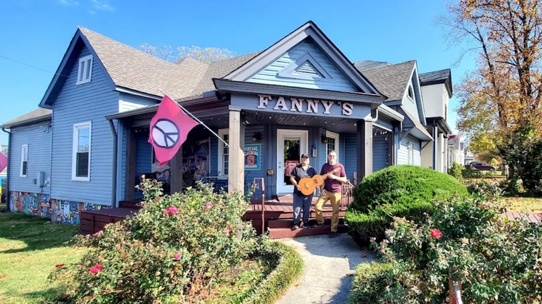 Two men holding a guitair outside of Fanny's House of Music in Nashville on a sunny day