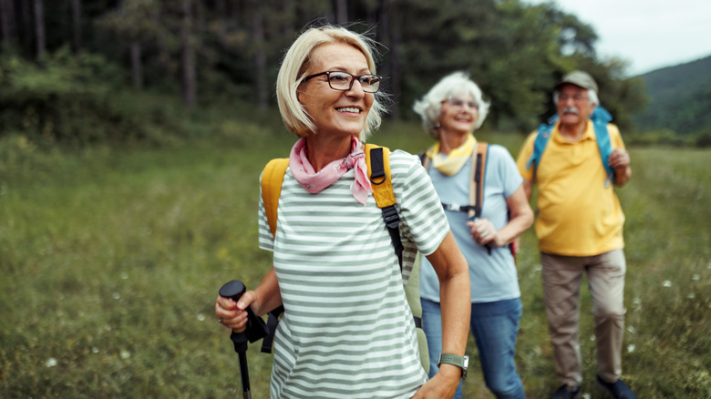 Mature woman enjoying hiking near a forest with two friends