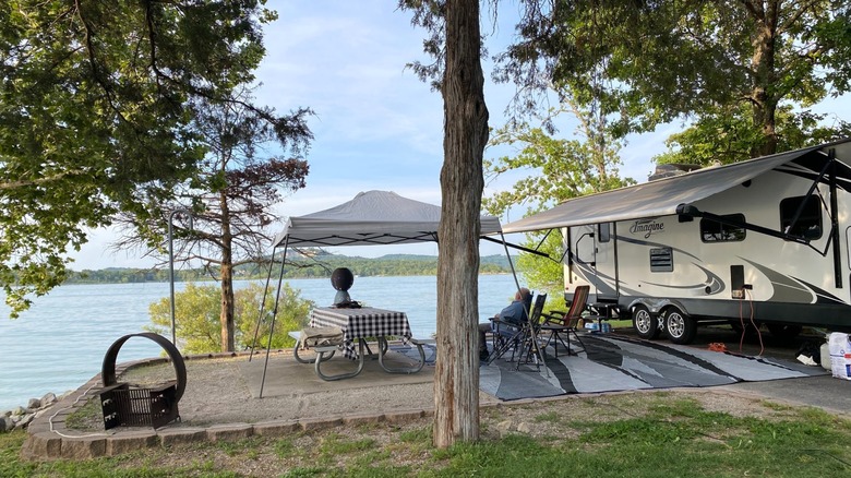 A waterfront campsite with an RV, picnic table, concrete pad, and canopy at Old Highway 86 Campground