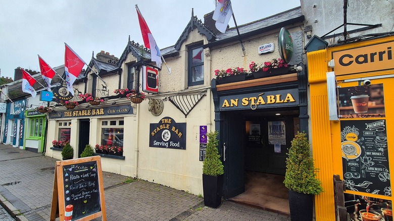 Flags and hanging baskets outside The Stable Bar on Main Street in Carrigaline, Ireland