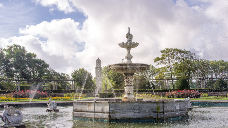 A fountain in the Italian gardens at Stanley Park sprays water on a cloudy day surrounded by flowers