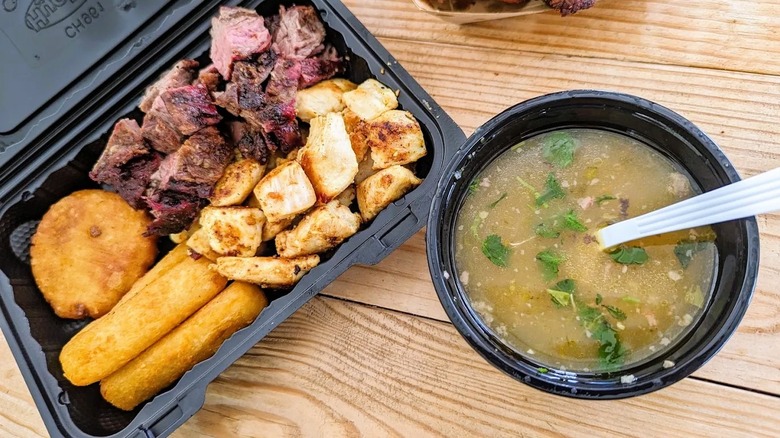 A platter with smoked meats and a side of soup, served at Sancocho y Leña Steak and Grill in Southwest Ranches, Florida
