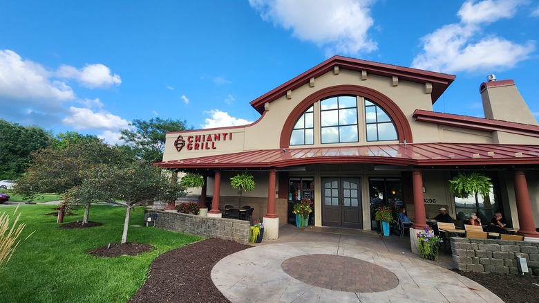 The entrance to a restaurant in Burnsville, with a few tables in front, a red roof, large windows, and blue skies