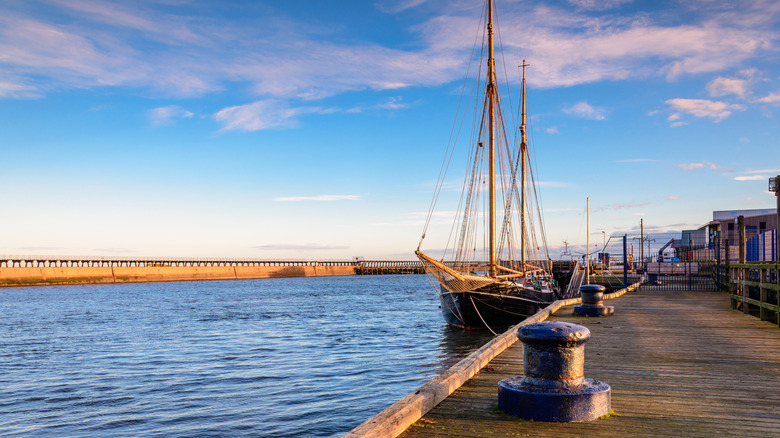 A replica tall ship docked in Blyth, England on a partly cloudy day.
