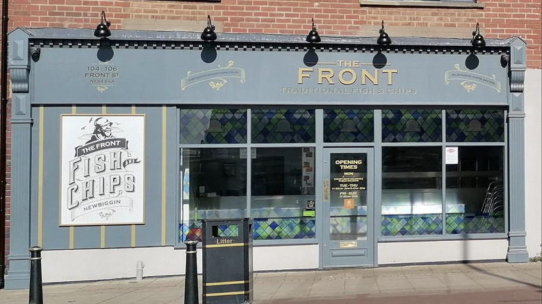 The exterior of The Front Fish & Chips Shop, a beloved local fish shop, on a bright day in Newbiggin-by-the-sea, England